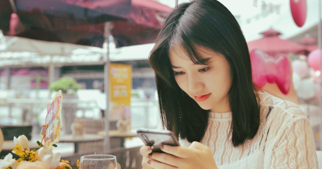 カフェでスマートフォンを確認する女性:マッチングアプリで会う前の安全チェック