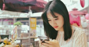 カフェでスマートフォンを確認する女性:マッチングアプリで会う前の安全チェック